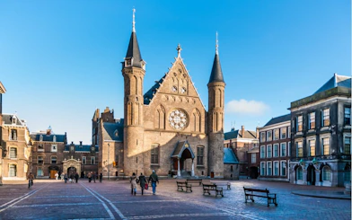 Binnenhof courtyard with Ridderzaal in The Hague, people walking.