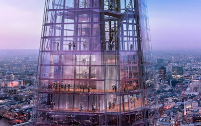 Visitors inside The Shard with panoramic views of London at dusk.