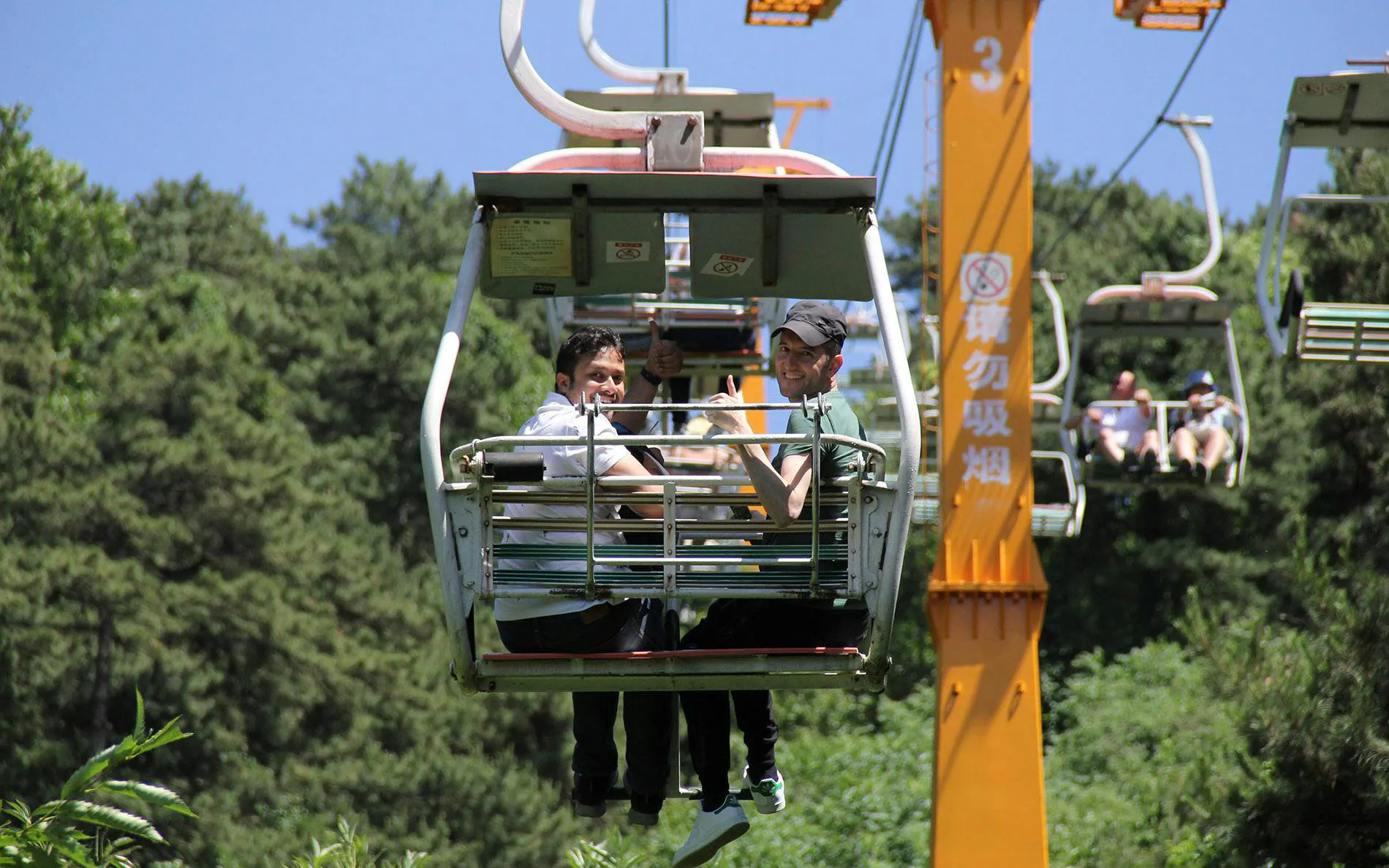 Visitors riding a cable car at Mutianyu Great Wall, surrounded by lush greenery.