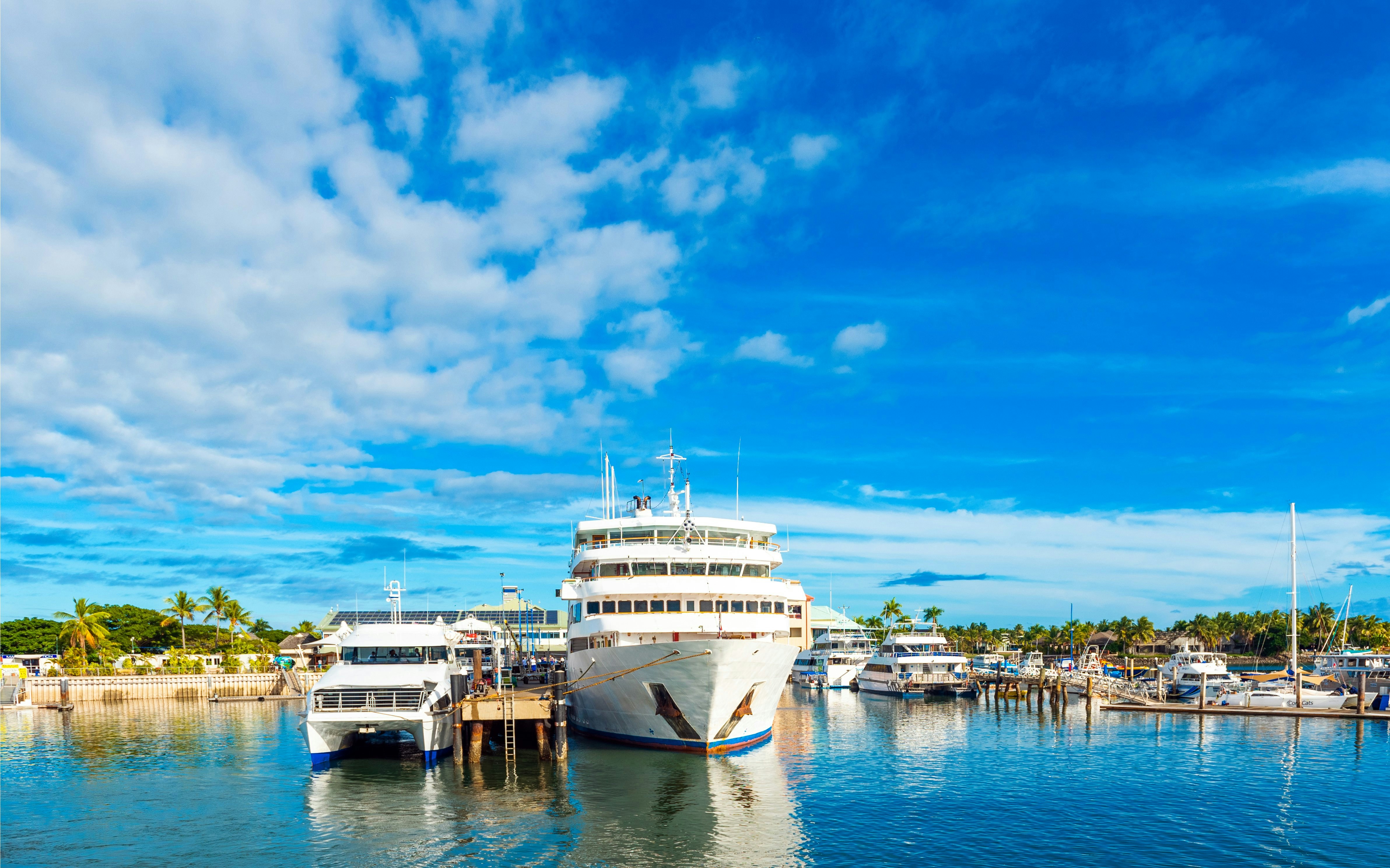 Boats docked at Denarau port in Nadi, Fiji, with clear blue skies.