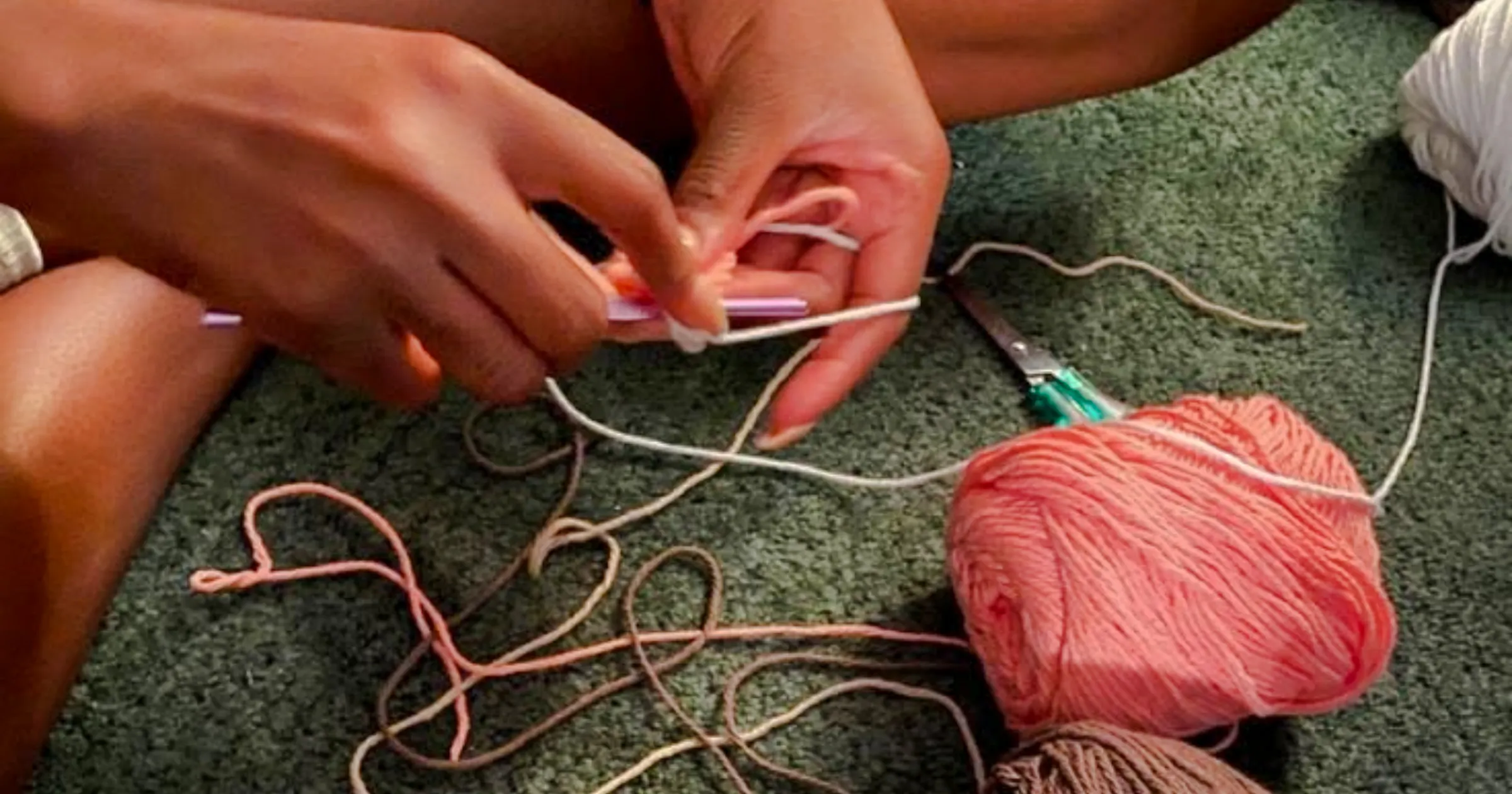 Hands crocheting with yarn at a workshop in Essaouira.