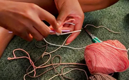 Hands crocheting with yarn at a workshop in Essaouira.