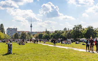 Crowd enjoying a sunny day at Mauerpark, Berlin with TV Tower in the background.