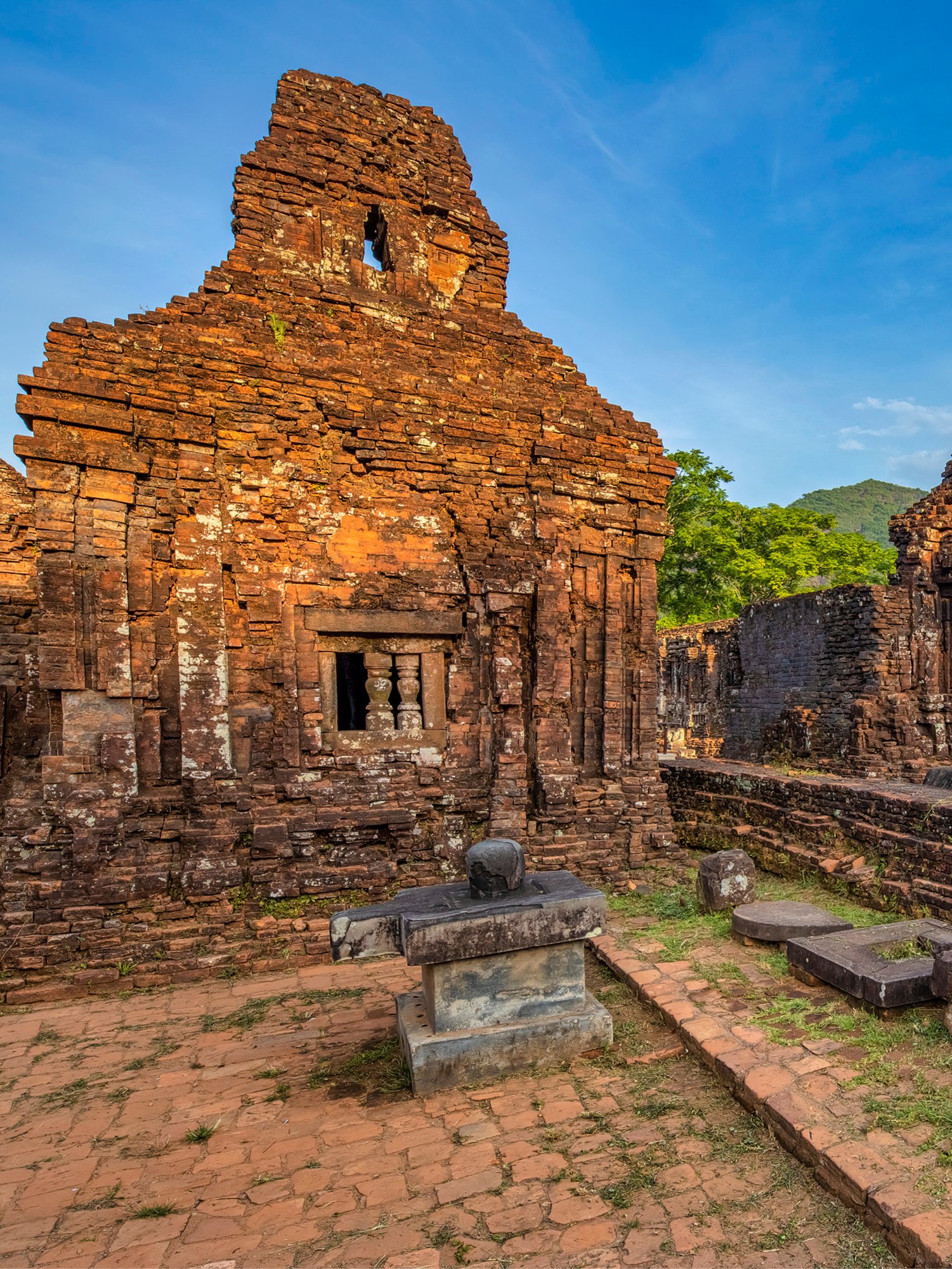 Ancient brick temple ruins at My Son Sanctuary, Vietnam, with stone altar in foreground.