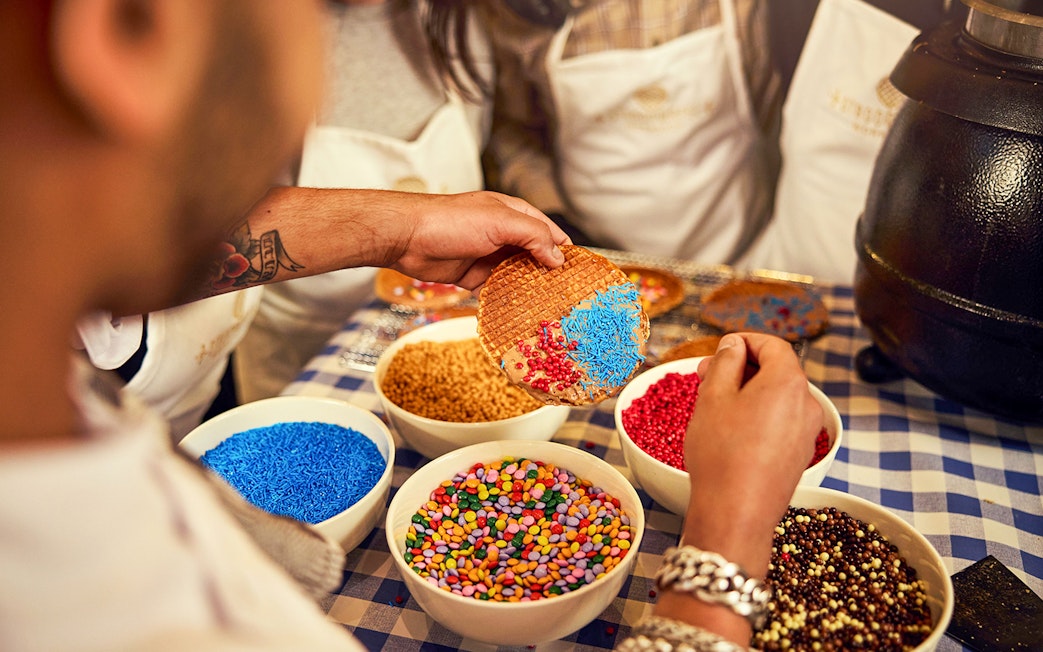 Dutch syrup waffle being decorated with colorful sprinkles at a workshop.