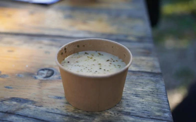 Traditional Polish soup served in a paper cup on a wooden table during a Zakopane tour.