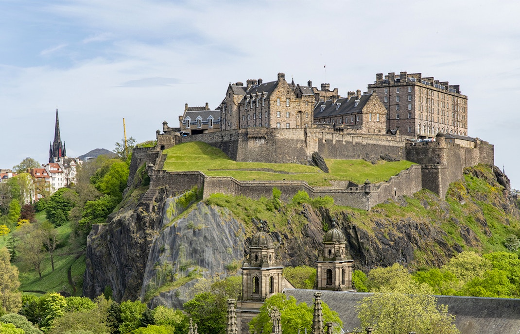 Edinburgh Castle on Castle Rock, surrounded by lush greenery, Scotland.