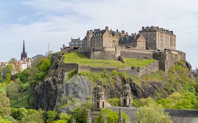 Edinburgh Castle on Castle Rock, surrounded by lush greenery, Scotland.