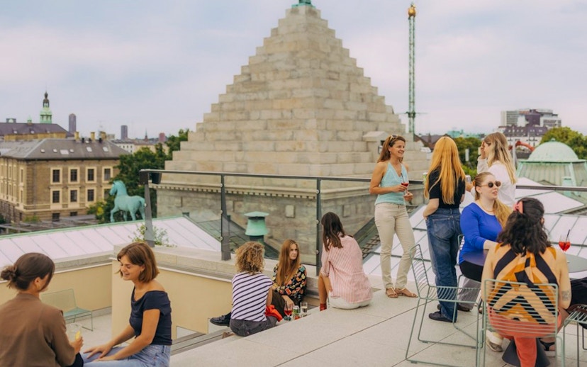 Group enjoying rooftop view in Copenhagen with historic architecture in the background.