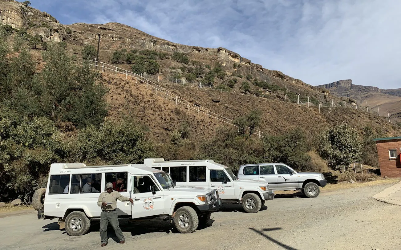 Off-road vehicles parked at Sani Pass with a guide, showcasing rugged mountain terrain near Durban.