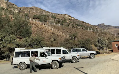 Off-road vehicles parked at Sani Pass with a guide, showcasing rugged mountain terrain near Durban.