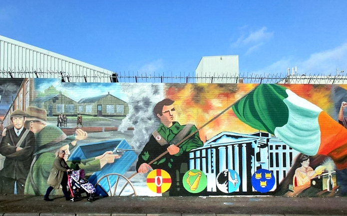 Belfast mural depicting historical political scenes and Irish flag on a guided taxi tour.