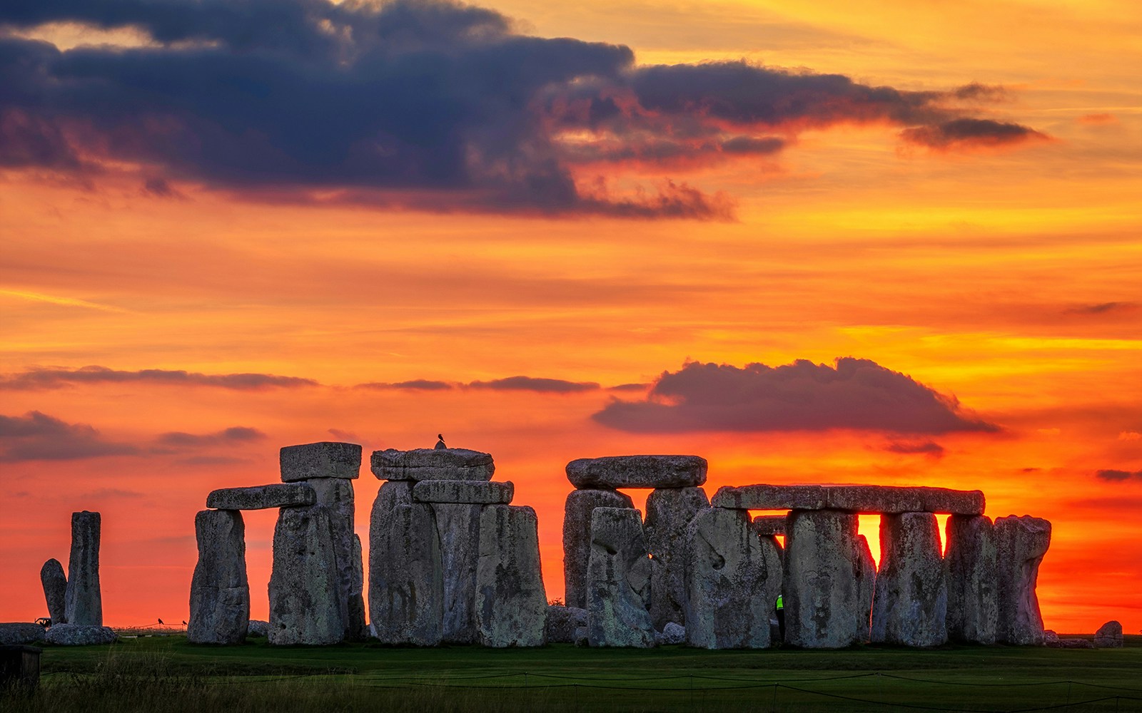 Stonehenge silhouetted against a vibrant sunset during the equinox in Wiltshire, England.