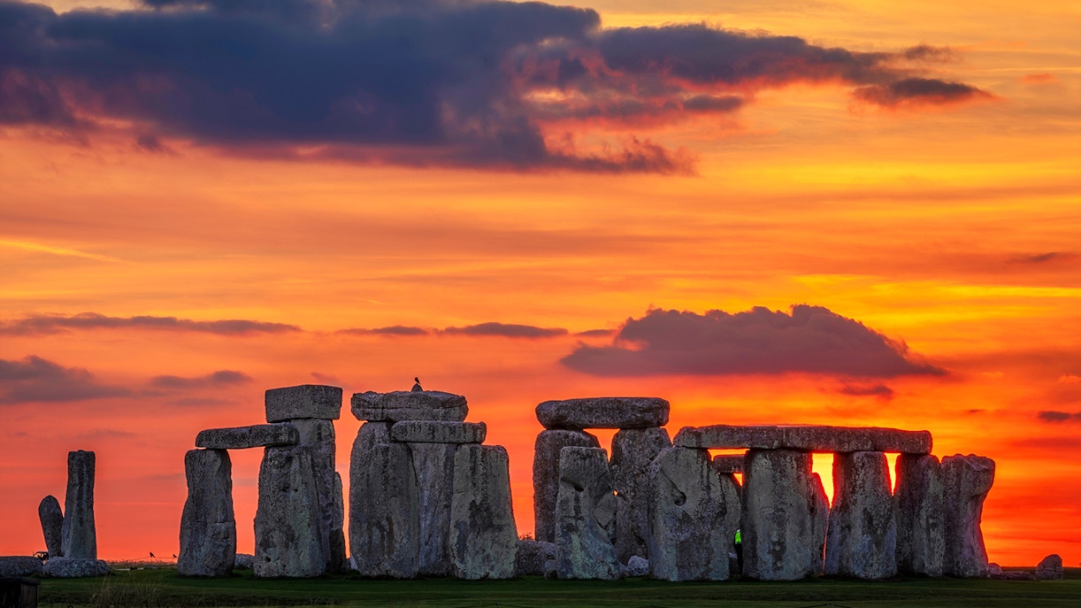 Stonehenge silhouetted against a vibrant sunset during the equinox in Wiltshire, England.
