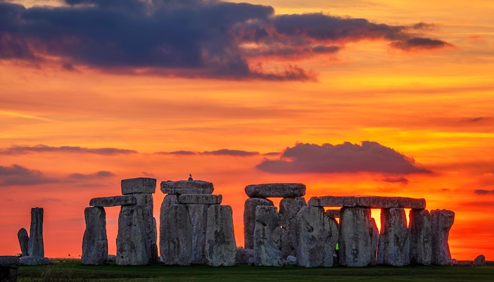 Stonehenge silhouetted against a vibrant sunset during the equinox in Wiltshire, England.