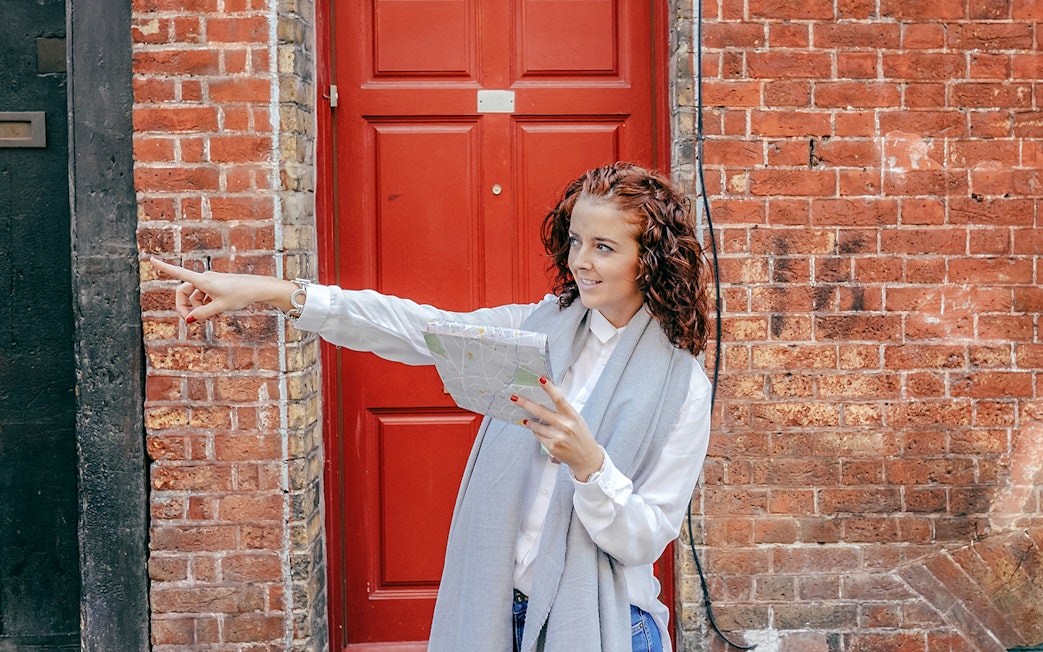 Tourist with map pointing during Westminster Walking Tour near red door.