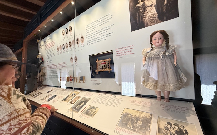 Exhibit display at Frida Kahlo Museum, featuring family photos and a doll in La Casa Roja, Coyoacán.
