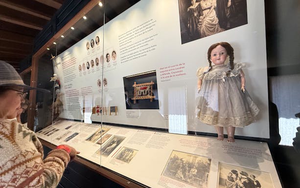 Exhibit display at Frida Kahlo Museum, featuring family photos and a doll in La Casa Roja, Coyoacán.