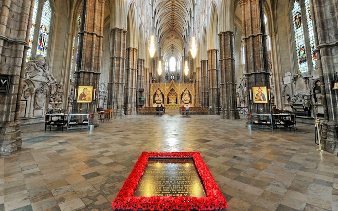 Tomb of the Unknown Soldier surrounded by poppies inside Westminster Abbey, London.