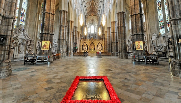 Tomb of the Unknown Soldier surrounded by poppies inside Westminster Abbey, London.