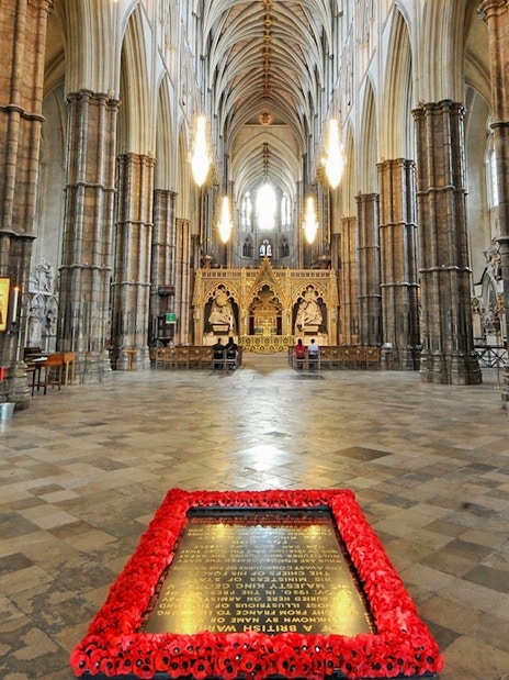 Tomb of the Unknown Soldier surrounded by poppies inside Westminster Abbey, London.