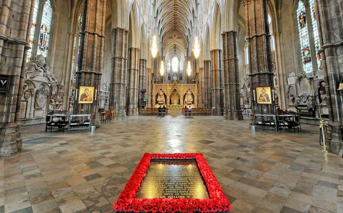 Tomb of the Unknown Soldier surrounded by poppies inside Westminster Abbey, London.