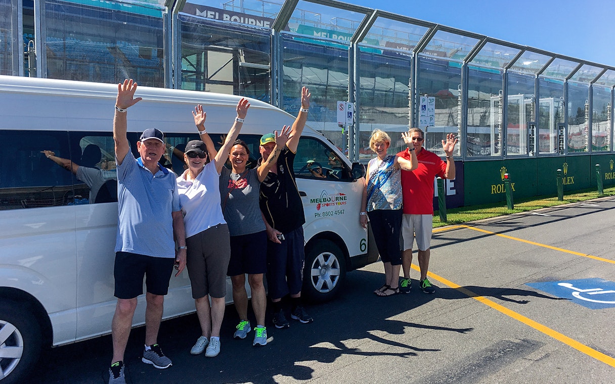 Group waving near Melbourne sports tour van at MCG.