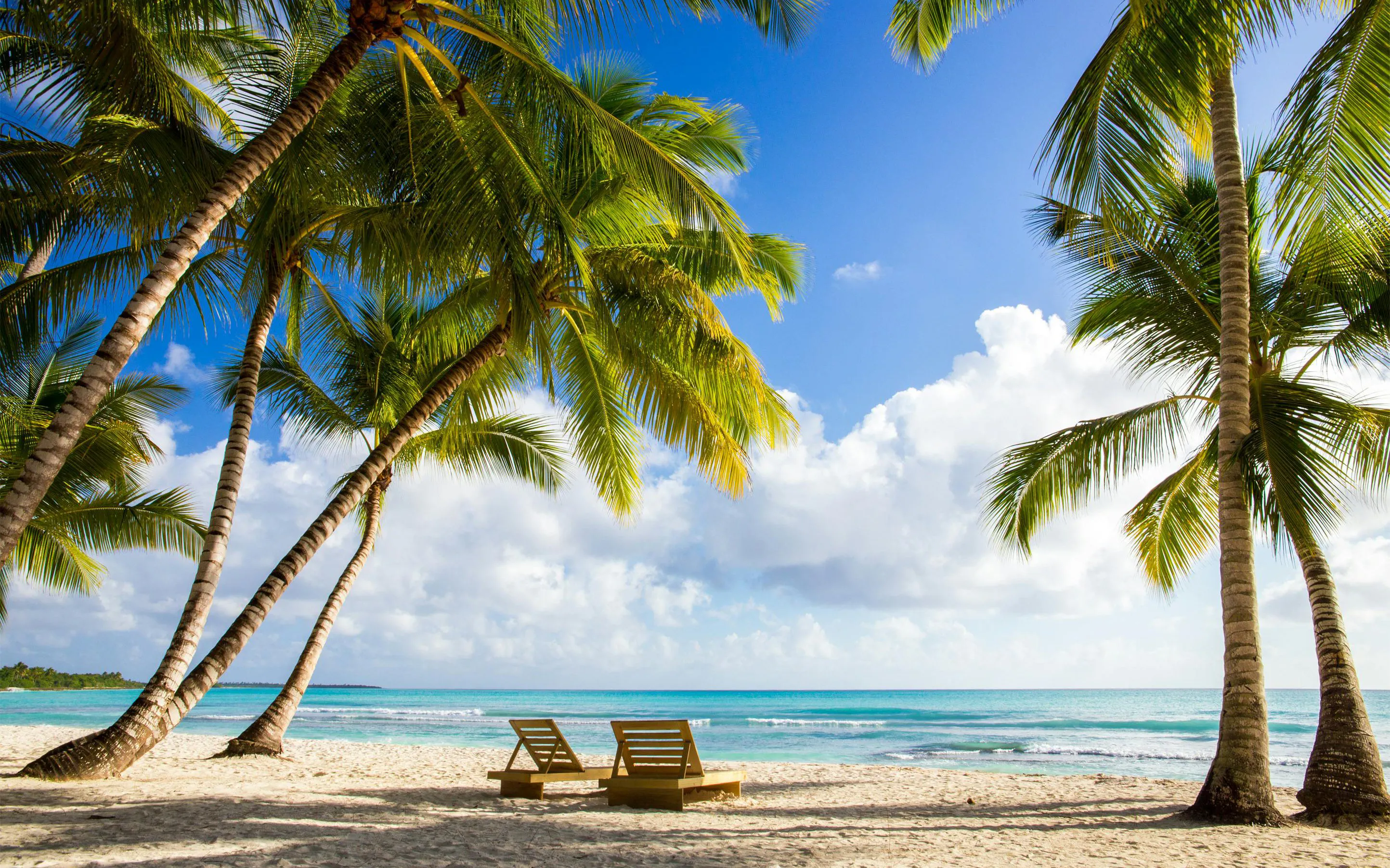 Sun loungers under palm trees on Saona Island Beach with turquoise sea.