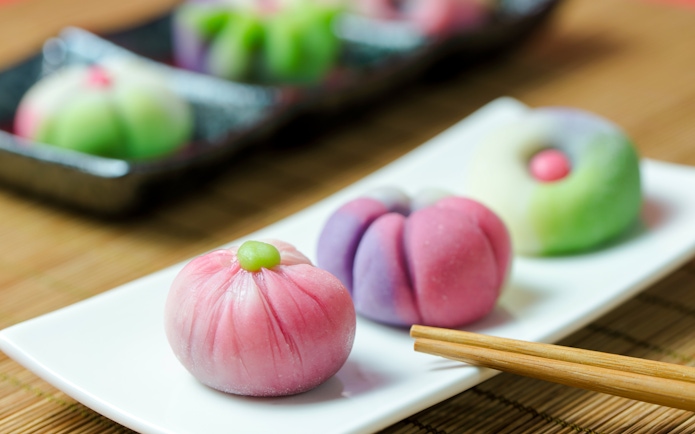 Japanese wagashi confections on a white plate with chopsticks.