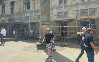 York city street with people near historical building under renovation.