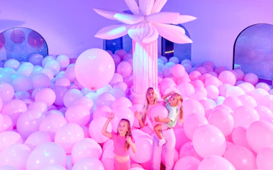 Visitors enjoying a room filled with pink balloons at Bubble Planet An Experience Museum.