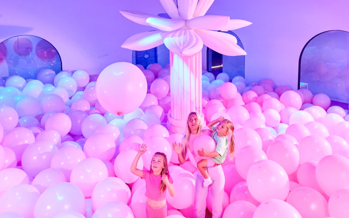Visitors enjoying a room filled with pink balloons at Bubble Planet An Experience Museum.