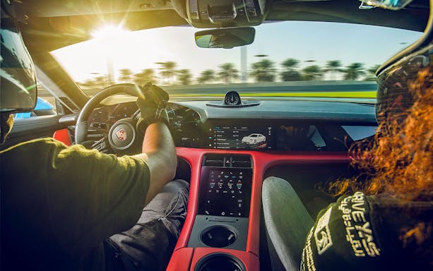 Porsche Taycan Turbo interior with driver on a racetrack, dashboard and steering wheel visible.