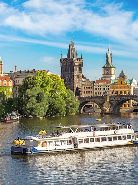 Prague Castle tour boat on Vltava River near Charles Bridge.
