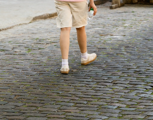 Person walking on cobblestone street in comfortable shoes, historic city center.