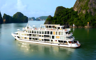5-star cruise ship sailing in Ha Long Bay, Vietnam, with limestone karsts in the background.