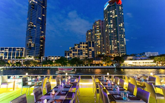 Dinner tables set on a cruise ship with city skyline view at IconSiam Pier No.4, Bangkok.