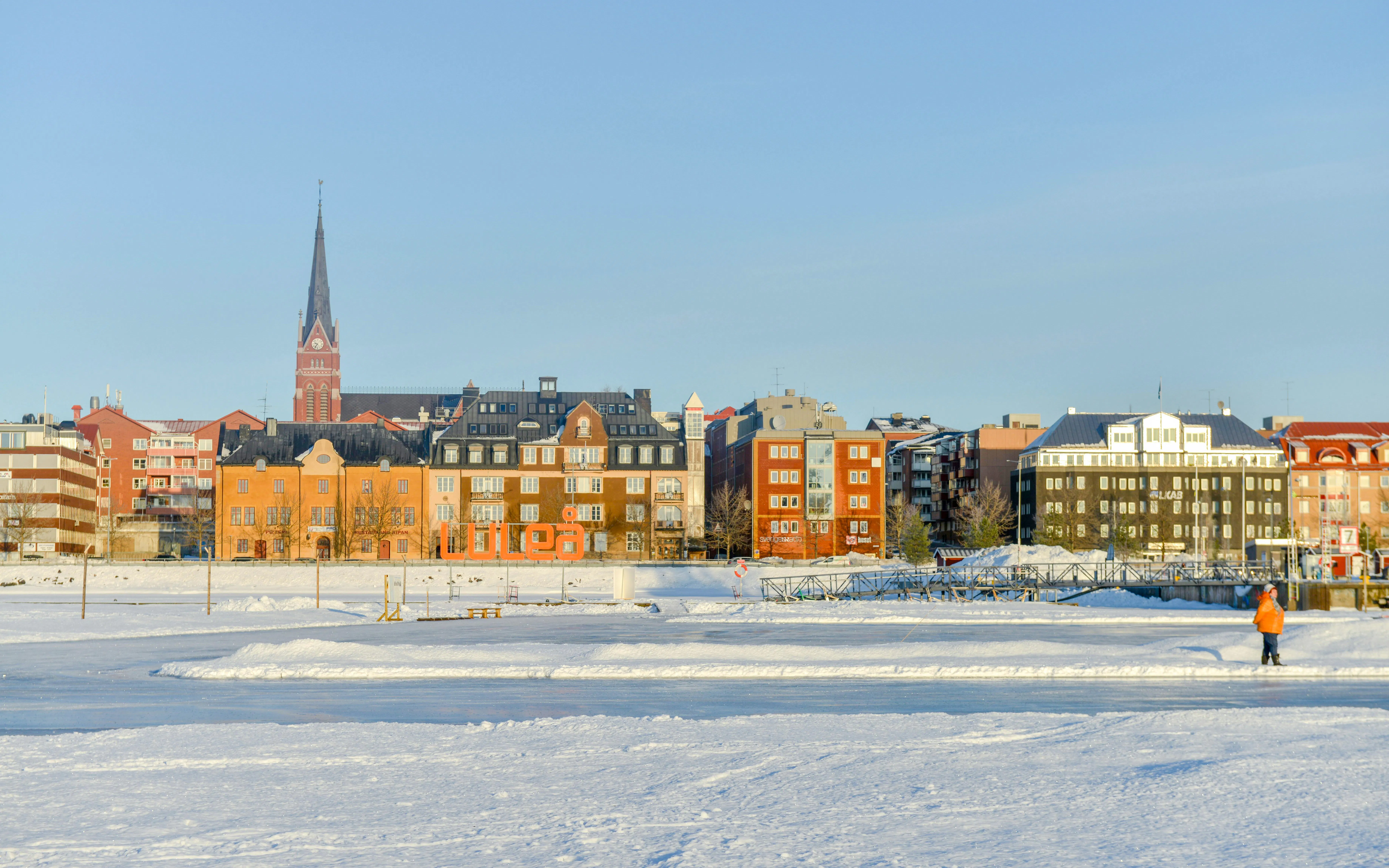 Frozen Arctic sea view with snowy landscape and Lulea town buildings in Sweden.