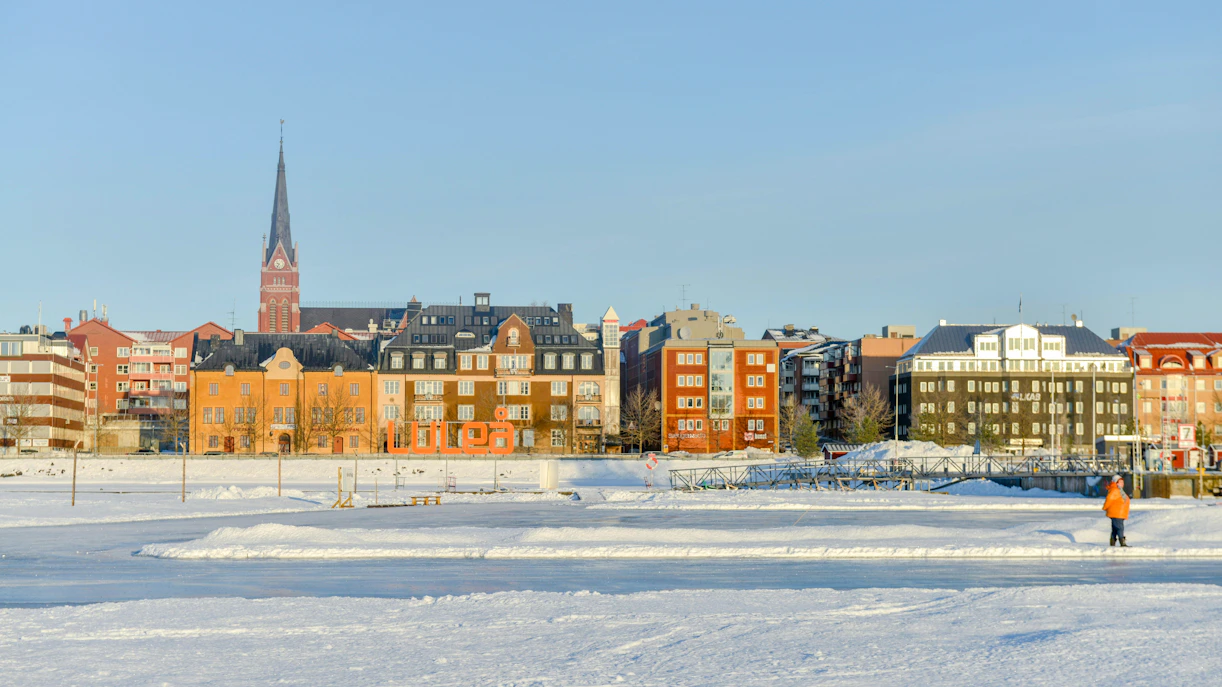 Frozen Arctic sea view with snowy landscape and Lulea town buildings in Sweden.