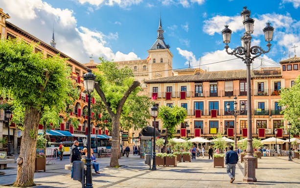 Toledo Stadtzentrum plaza with historic buildings and people walking.