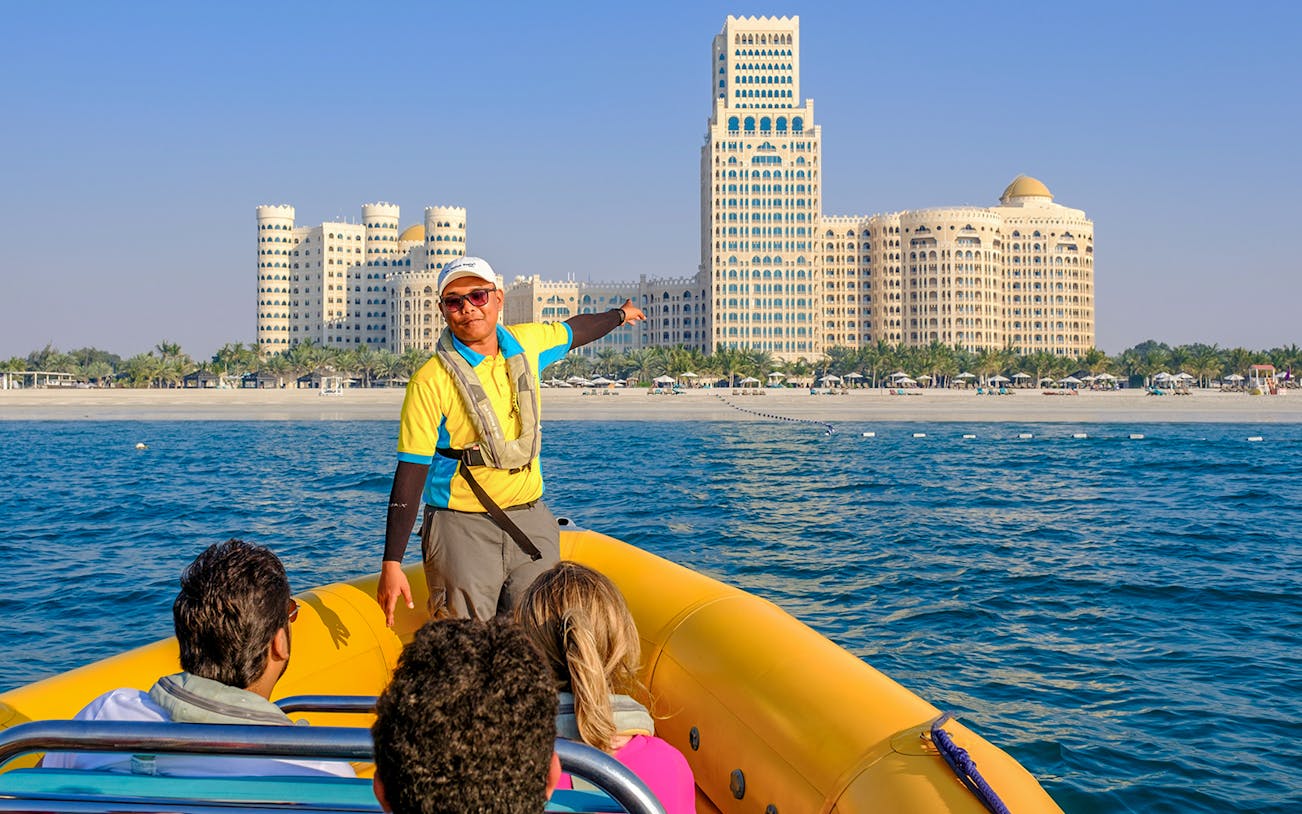 Speed boat tour guide pointing at Al Marjan Island skyline, Ras Al Khaimah.