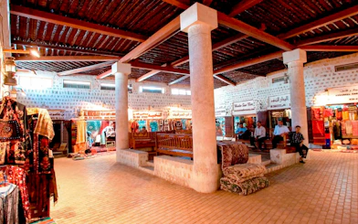 Sharjah market interior with traditional textiles and visitors seated on benches.