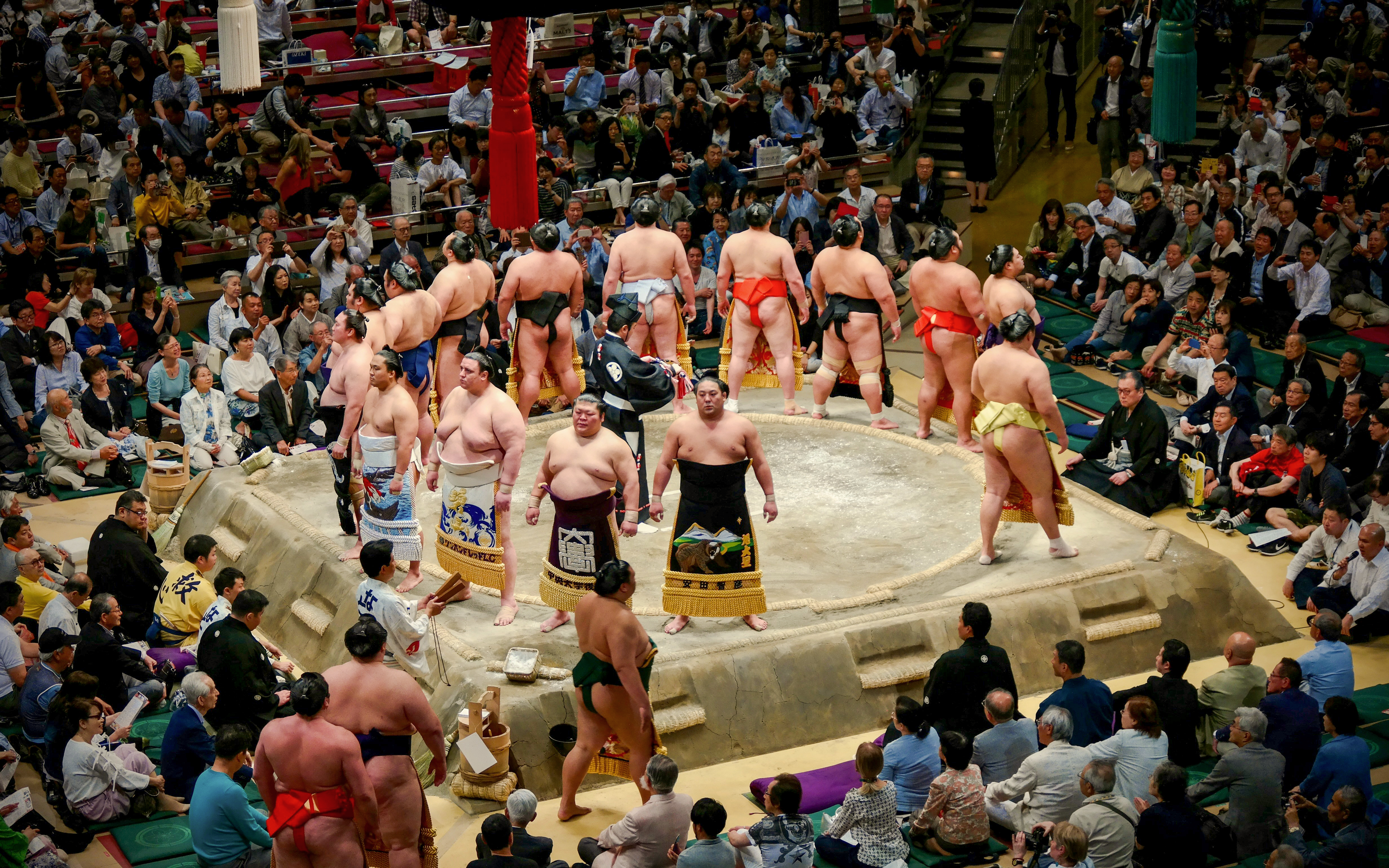 Sumo wrestlers prepare for a match in a crowded Japanese arena.