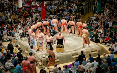 Sumo wrestlers prepare for a match in a crowded Japanese arena.