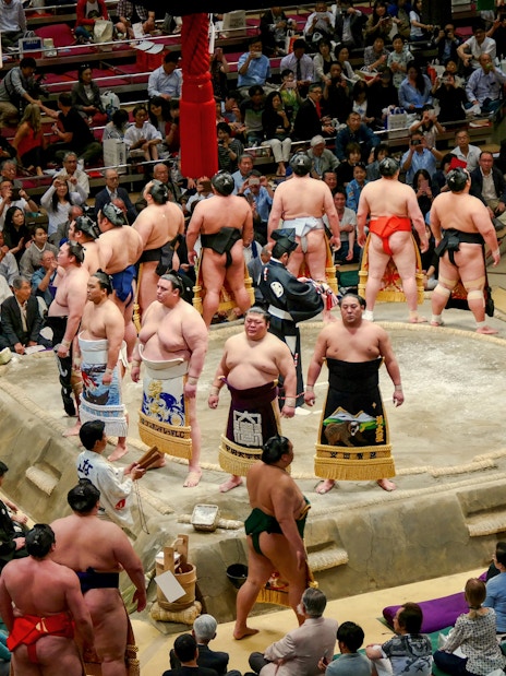 Sumo wrestlers prepare for a match in a crowded Japanese arena.