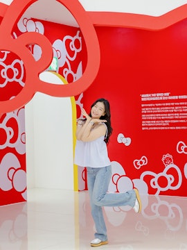 Tourist posing under red Hello Kitty arch at Hello Kitty Island.