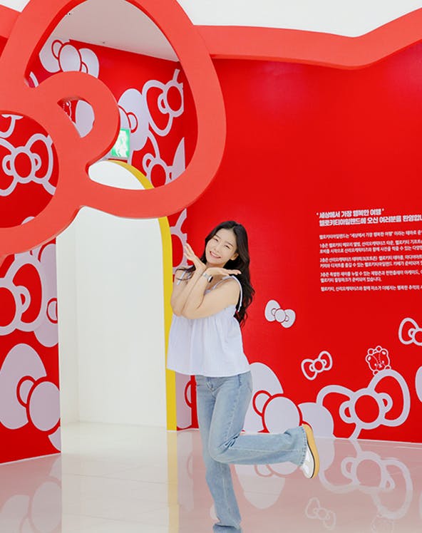 Tourist posing under red Hello Kitty arch at Hello Kitty Island.
