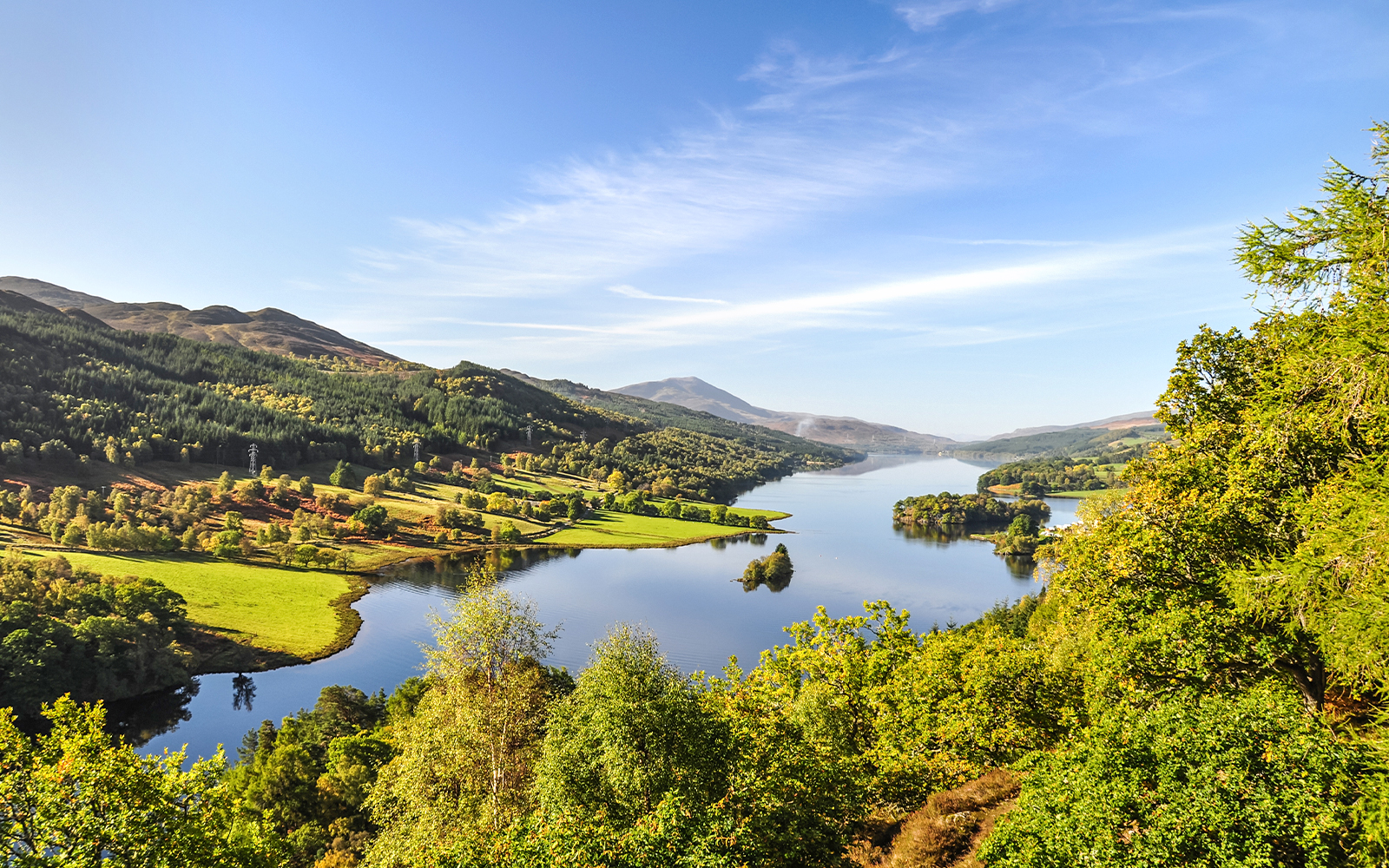 View of Loch Tummel from Pitlochry, Scotland, with lush greenery and distant hills.