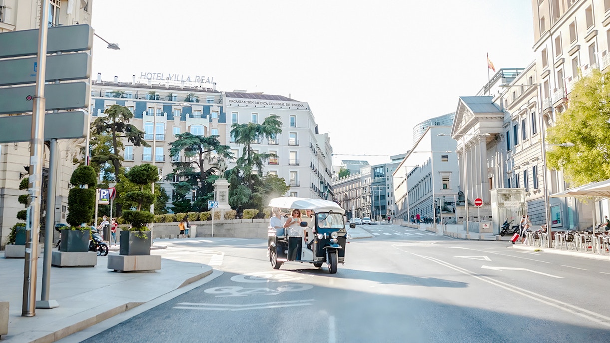 Electric tuk-tuk with tourists on a street near Hotel Villa Real, Madrid, Spain.