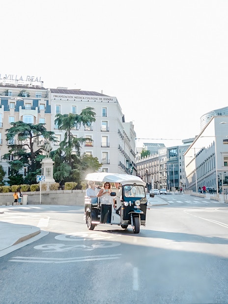 Electric tuk-tuk with tourists on a street near Hotel Villa Real, Madrid, Spain.